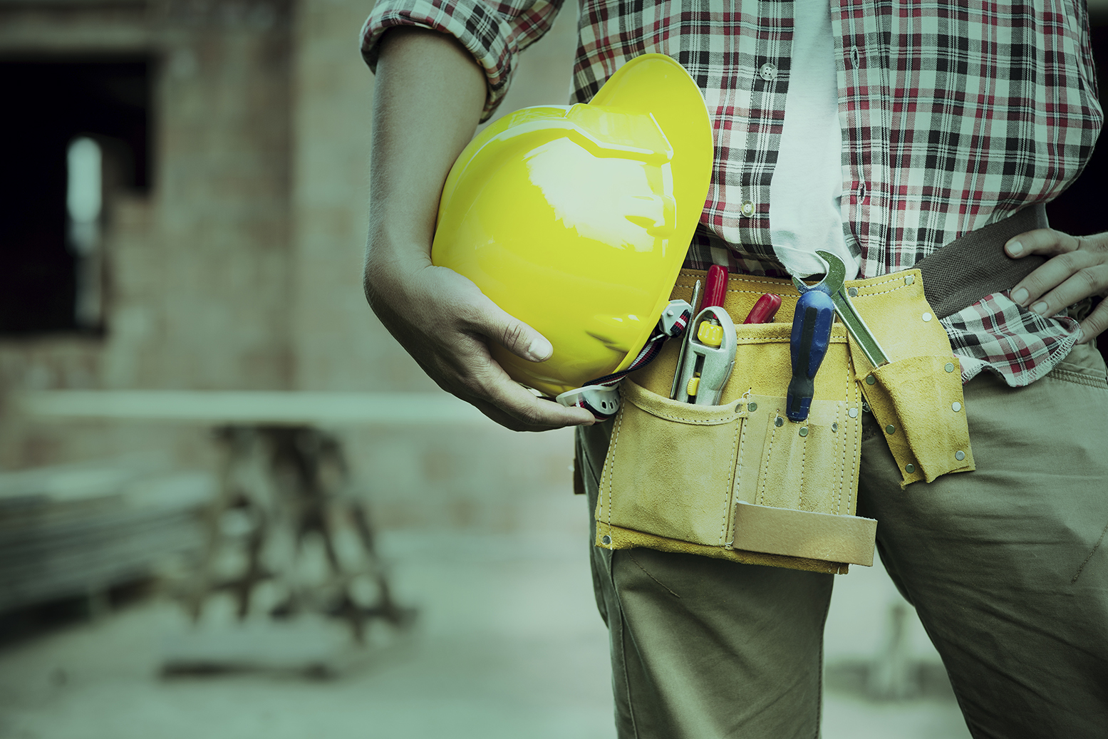 A construction worker holding a hard hat in one hand by his leg