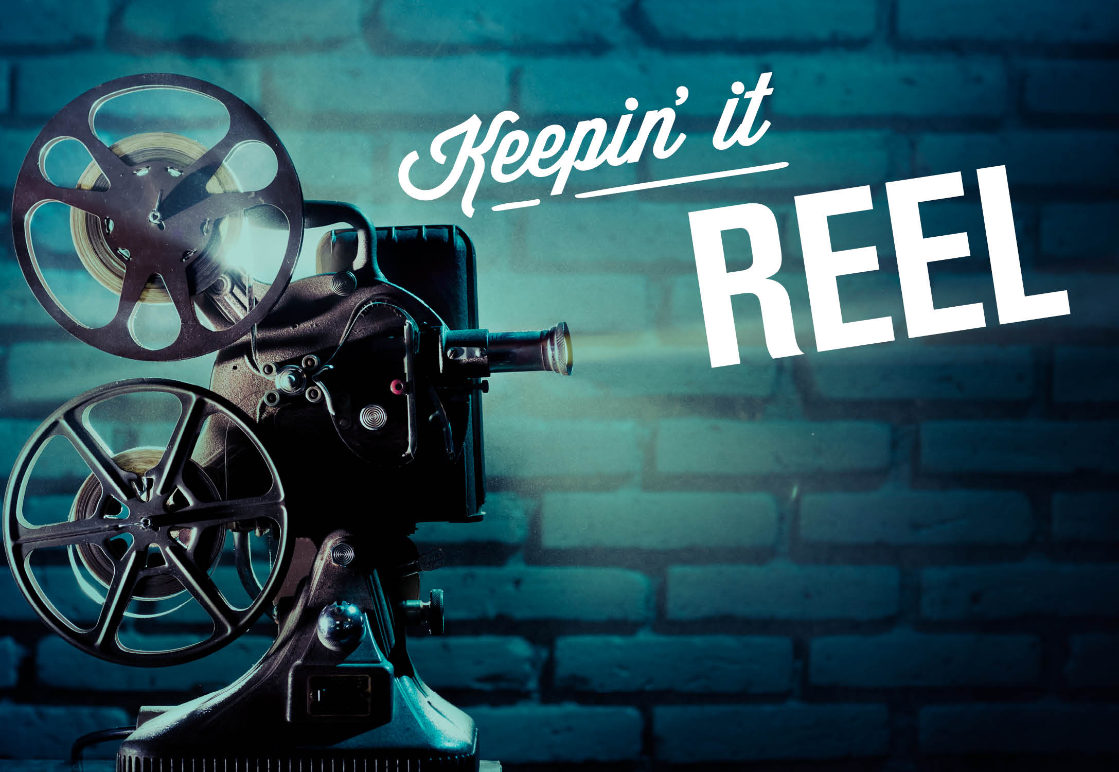 A film projector with the text 'Keepin' it Reel' on a brick wall