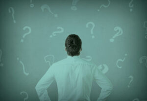 A person staring confused at a wall with question marks.