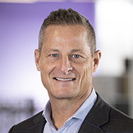 Dan Keough - a man in a suit smiling for a professional headshot photo