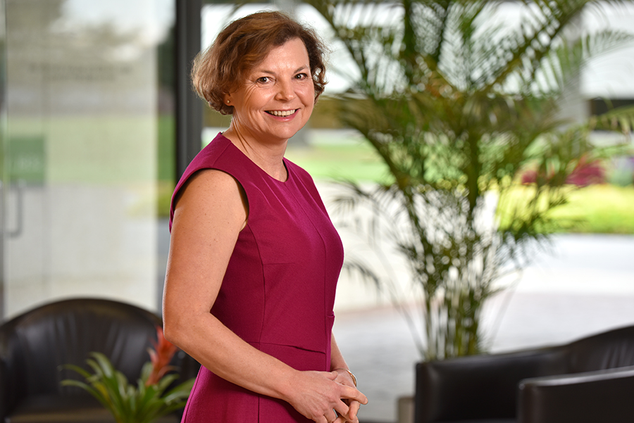 Ellen Willadsen in a professional red dress with a greenery background
