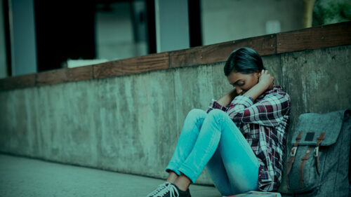 A girl sitting on the floor struggling with her mental health.