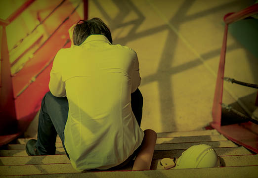 A construction worker crouched thinking about his mental wellbeing