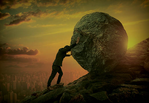A man pushing a rock up a hill