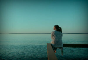A person sitting by the ocean thinking of their wellbeing