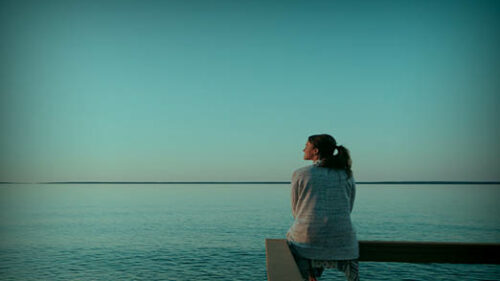 A person sitting by the ocean thinking of their wellbeing