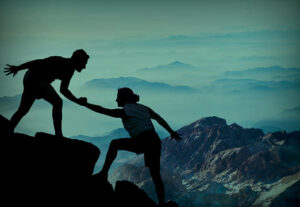 Two rock climbers helping each other