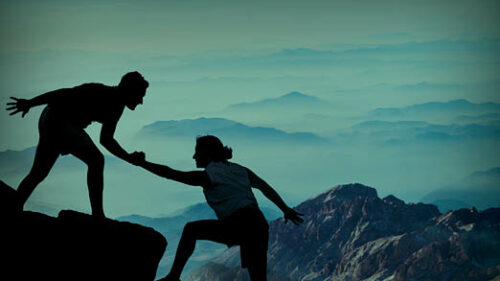 Two rock climbers helping each other