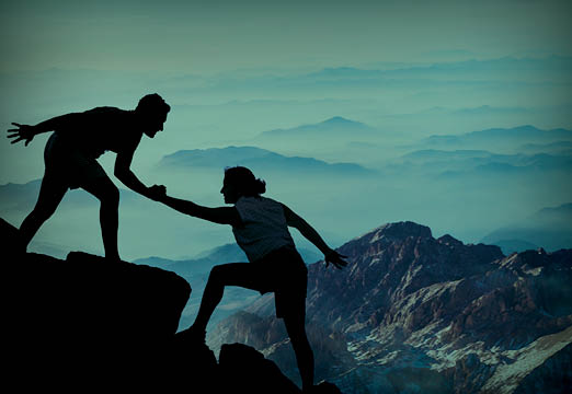 Two rock climbers helping each other