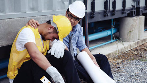 Two construction workers looking sad on a job site.