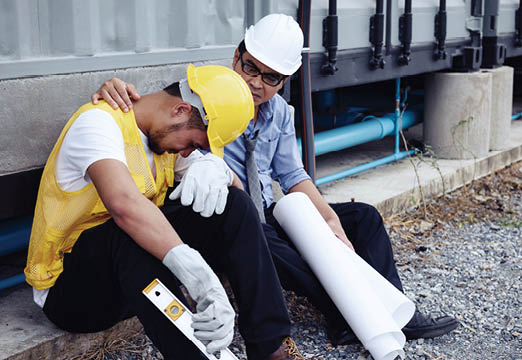 Two construction workers looking sad on a job site.