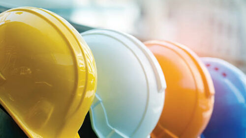 A row of hard hats that are yellow, white, orange and blue