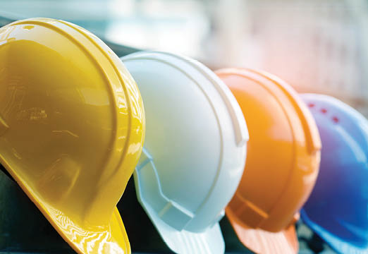 A row of hard hats that are yellow, white, orange and blue