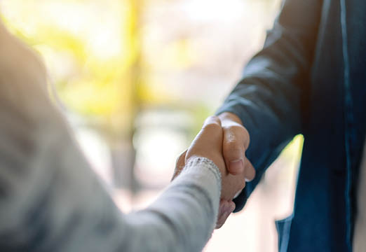 Two people wearing business shirts shaking hands