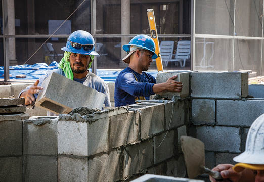 two brick layers working outside on a construction site