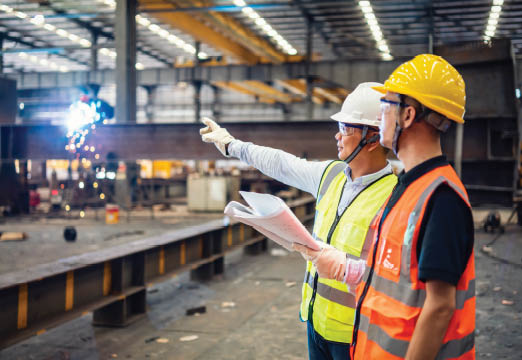 Two workers wearing safety vests in a warehouse setting