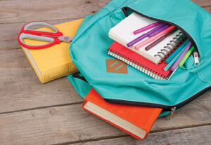 A book bag full of notebooks and pencils on the ground