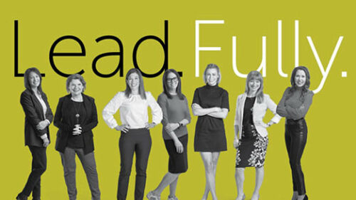 Lead.Fully. text with the women leadership at Holmes Murphy standing in front of the words on a green background.