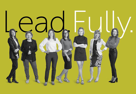 Lead.Fully. text with the women leadership at Holmes Murphy standing in front of the words on a green background.