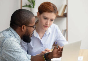 Two employees talking while looking at a laptop.
