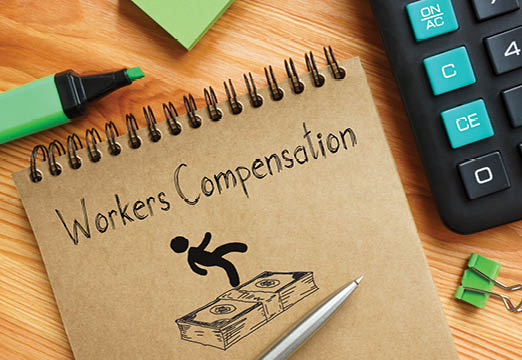 A notebook with workers compensation written on it with a cartoon of a person and money