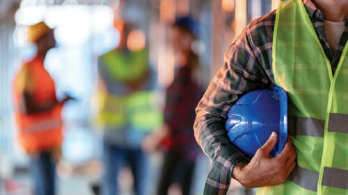 A construction worker holding his hard hat on the job site