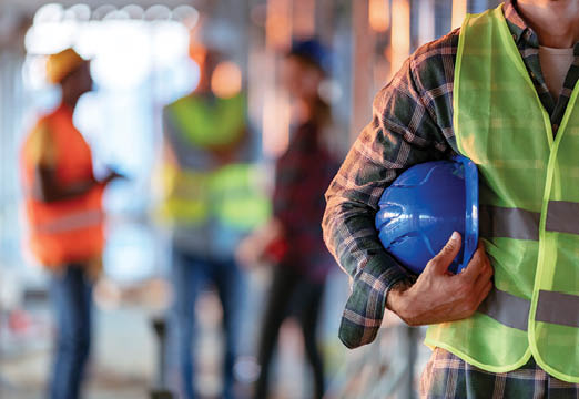 A construction worker holding his hard hat on the job site