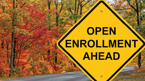A road sign that says Open Enrollment Ahead on a fall scenic road