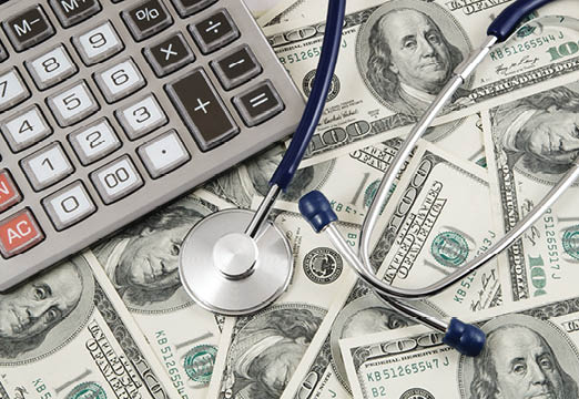 A calculator and a stethoscope sitting on top of a lot of dollar bills.