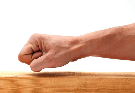 A fist knocking on a wood slab