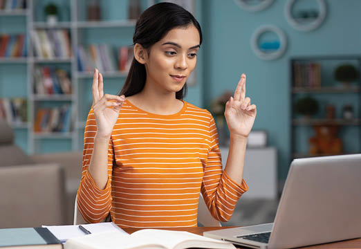 A woman crossing her fingers at a desk working