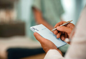 The hands of a doctor writing on the prescription pad.
