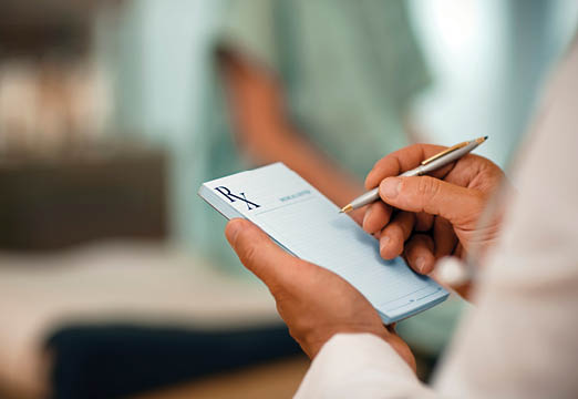 The hands of a doctor writing on the prescription pad.