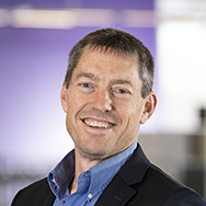 Jay Freiermuth - a man in a suit without a tie smiling for a professional photo