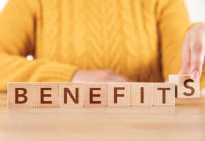 A woman with 'Benefits' spelled out on wooden blocks in front of her.