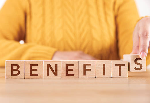 A woman with 'Benefits' spelled out on wooden blocks in front of her.