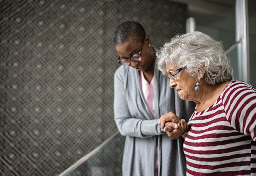 A caregiver helping an older woman down the stairs