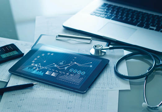 A tablet on a desk with graphs on it next to a stethoscope