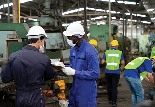 manufacturing workers wearing protective equipment as they work.