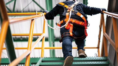 A worker climbing construction stairs wearing a safety harness