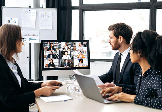 Office workers in a conference room talking to people on a zoom call.