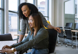 Two female employees looking at a computer together in collaboration
