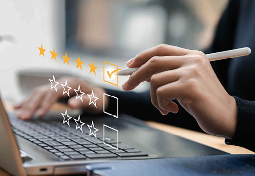 A person typing a 5 star review on a laptop.