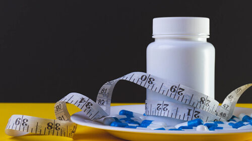 A bottle of prescription medication with a measuring tape.