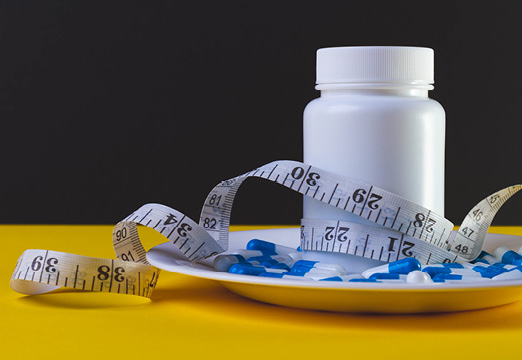 A bottle of prescription medication with a measuring tape.