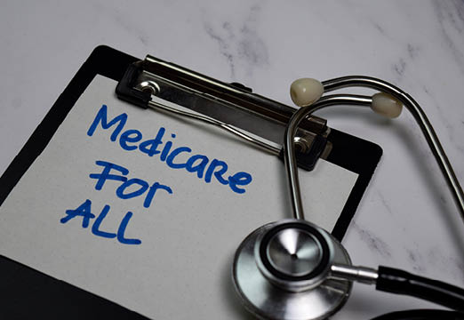 A notepad with medicare for all written on it next to medical equipment on a counter