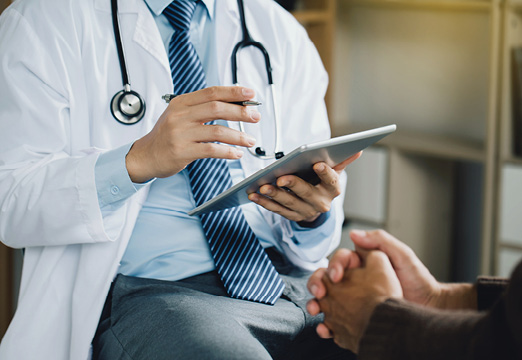 doctor holding an electronic device, discussing with a patient