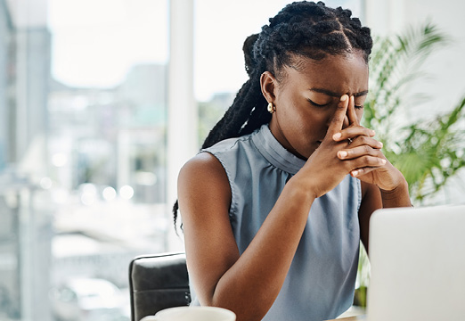 A Black woman at her office desk thinking deeply
