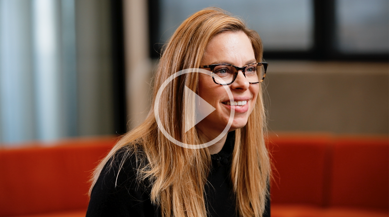 A video thumbnail of Erin Hunt, a woman with strawberry blonde hair sitting on a red couch.