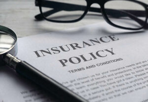 Insurance paperwork on a desk with glasses.